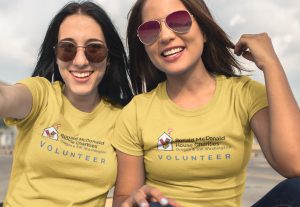 Two females taking a selfie wearing yellow Ronald McDonald House Charities Volunteer shirts