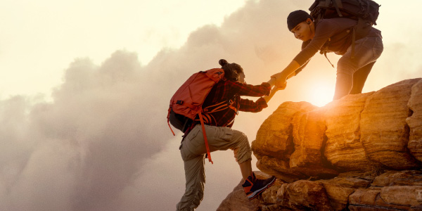 A hiker reaches out to help someone in need while climbing.