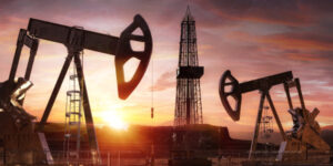 Two oil rigs generate energy while the sun sets.