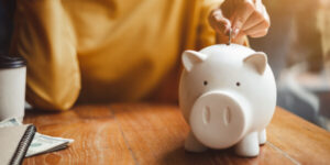 A young woman drops a coin into her piggy bank.