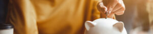 A young woman drops a coin into her piggy bank.