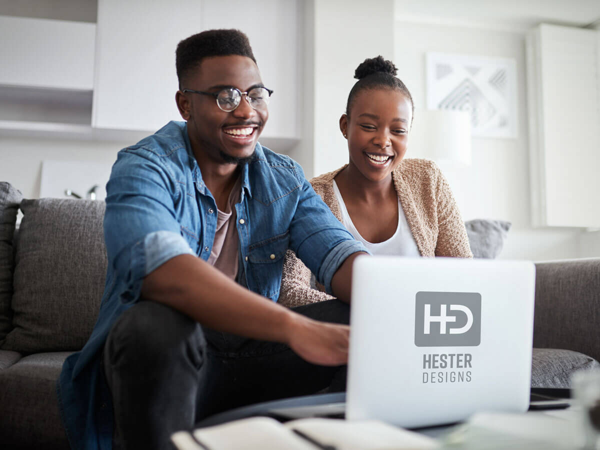 Black couple sitting on a couch starts a business online planning their website with accessibility in mind.