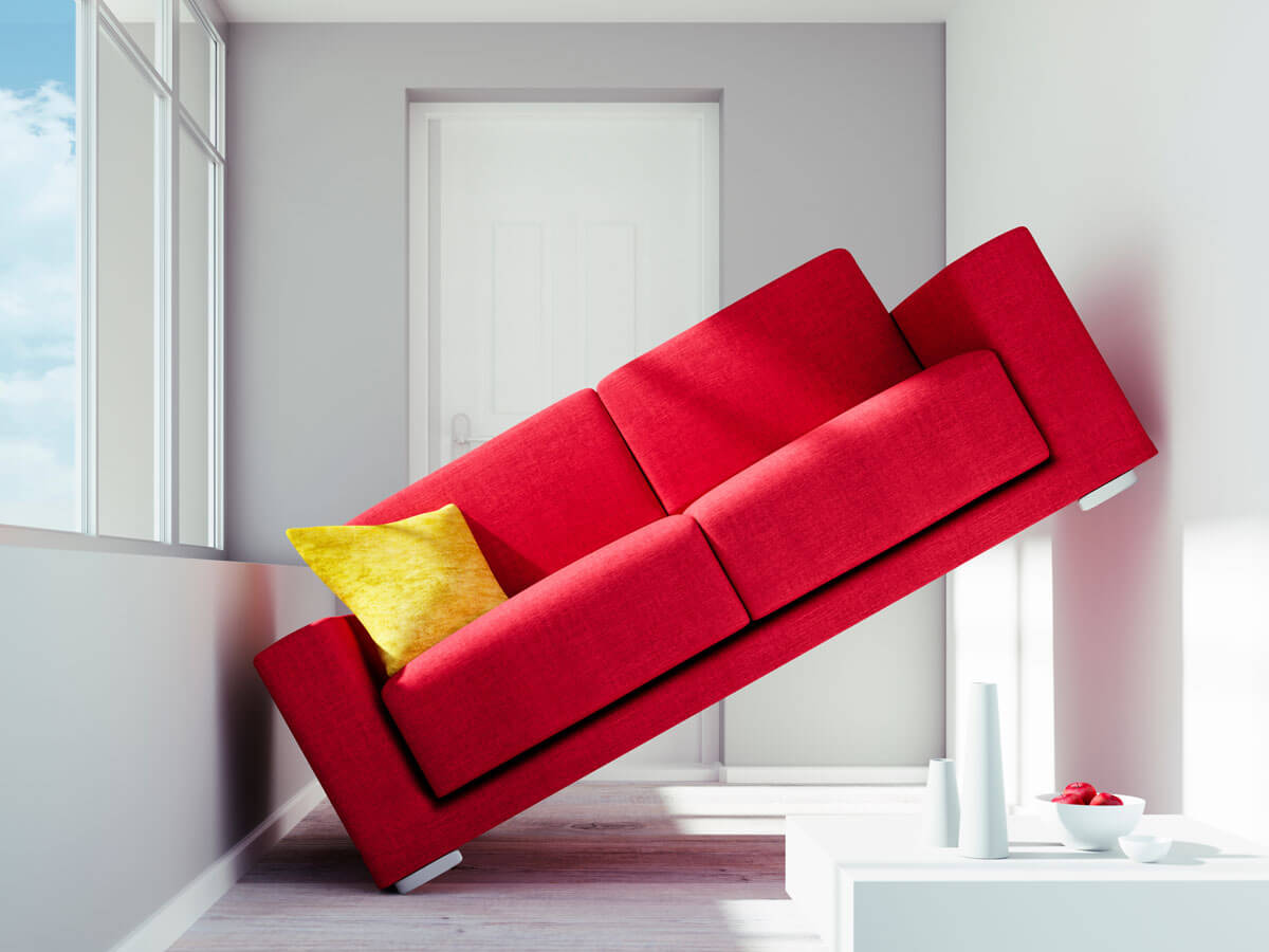 A red couch sits sideways too big for the space it sits in.