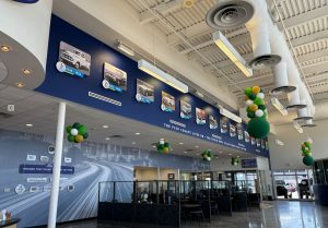 Hester Designs dealership interior design includes dramatic wall paper, a timeline, and corporate brand display.