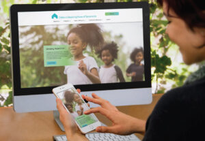 female adult viewing children's receiving home of Sacramento website on iMac screen and iPhone screen