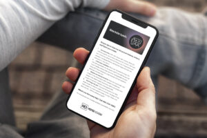 man holding iPhone in hand, sitting casually with leg resting on other knee, reading latest Hester Designs e-newsletter