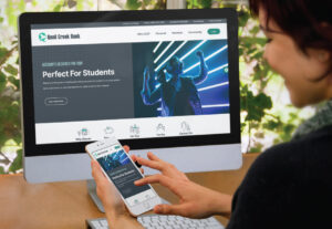 quail creek bank new website displayed on iMac screen and smartphone screen held in female adult's hand