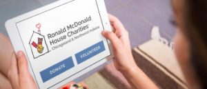 Ronald McDonald House Charities Chicagoland Logo displayed on iPad being held by female user