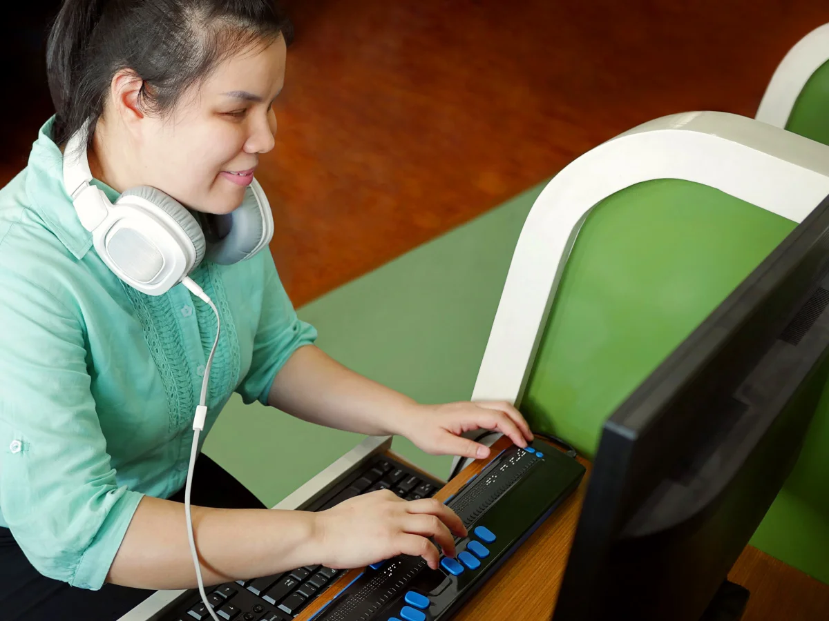 visually impaired young adult female using braille display to read a webpage